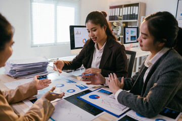 Businesswomen are discussing financial data and analyzing charts during a productive meeting in a modern office, fostering collaboration and strategic decision-making
