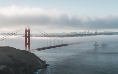 The Golden Gate Bridge, shrouded in fog, with the San Francisco skyline in the distance.