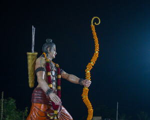 A statue of Lord Rama holding a decorated bow and arrow, adorned with garlands, symbolizing the victory of good over evil in Dussehra celebrations, associated with Ravana Vadh.