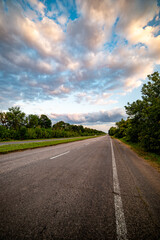 A picturesque asphalt road winds through lush green trees, inviting travelers into a serene natural landscape. Perfect for themes of adventure, travel, or nature exploration.