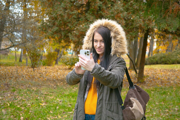 A young, beautiful girl travels in nature, admires the beauty of the autumn forest with admiration,...