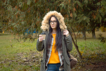 A young, beautiful girl travels in nature, admires the beauty of the autumn forest with admiration,...