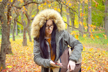A young, beautiful girl travels in nature, admires the beauty of the autumn forest with admiration,...