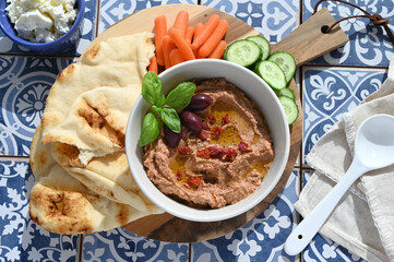 Sun-dried tomato kalamata olive hummus with naan, carrots and cucumbers Mediterranean tiles, homemade recipe