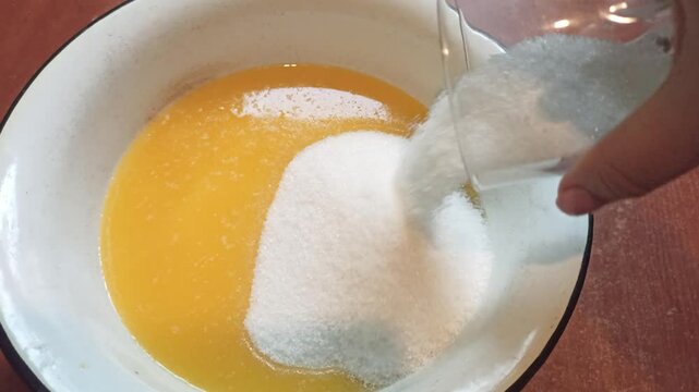 Proccess of making shortbread dough for a pie, putting sugar into melted butter. Horizontal 4k footage