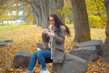 A young, beautiful girl travels in nature, admires the beauty of the autumn forest with admiration,...