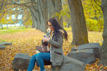 A young, beautiful girl travels in nature, admires the beauty of the autumn forest with admiration,...