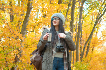 A young, beautiful girl travels in nature, admires the beauty of the autumn forest with admiration,...