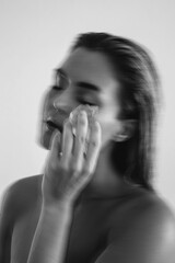 Creative shot with motion blur effect of young woman applying ice to her face