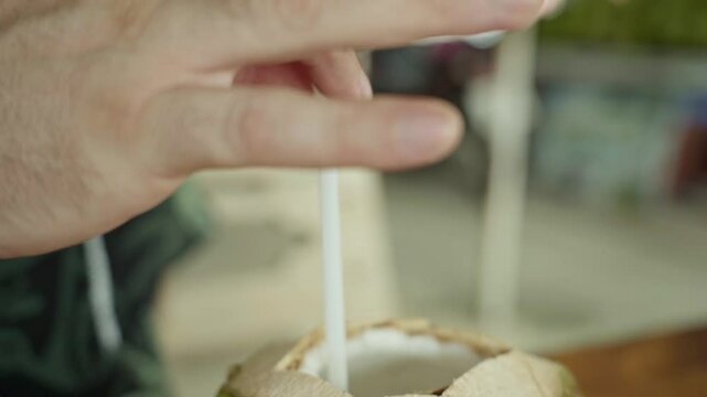 italian tourist man with hawaii shirt drinking with a strew from a young coconut fruit daytime