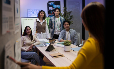 Group of young Asian professionals collaborating on a late-night project meeting in a modern office. Brainstorming innovative ideas for a new business venture.