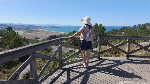 Tourist woman enjoying the views of the Galician coast from the top of a mountain viewpoint, Pontevedra.