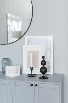 Assorted picture frames, candlesticks and ornaments on a sideboard under a mirror in a living room