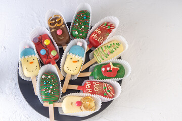 Christmas dessert. Sweet food. Cheesecake on a stick in the shape of ice cream. Children's treat in winter. Candy Christmas tree, snowman, deer and Santa Claus. Gingerbread cookies. White background.