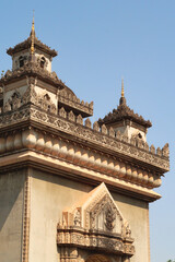 The elaborate facade, roof and turrets, towers of the Patuxai Monument, decorated with a lot of stucco in different shapes and patterns, Vientiane, Laos