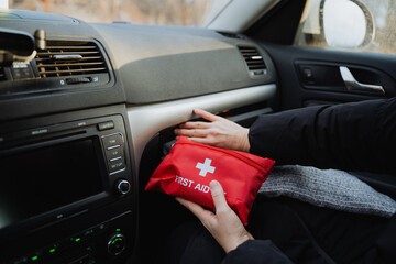 A person is currently in their car, and they are holding a first aid kit, which is an important...