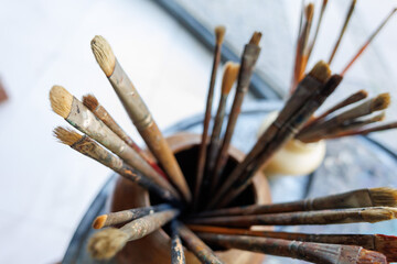 Artist's brush collection displayed in a wooden holder on a colorful table in a creative workspace