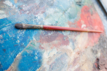 Painting palette with brush resting on vibrant colors in an artist's studio