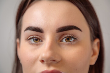 Beautician showing perfect eyebrows after microblading treatment