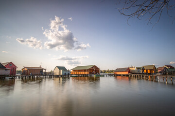 Wooden houses in the water. Holiday resort in the lake at sunset. Long wooden walkways lead to the...
