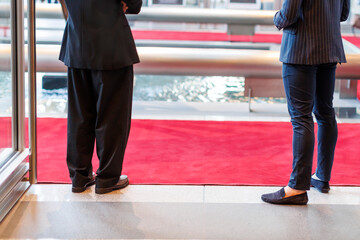 Fototapeta premium Two individuals standing on a red carpet near a fountain in a luxurious venue during a formal event