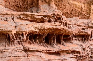 Close-up of bizarre sandstone formations, rough surfaces, curved lines, and erosion marks. The shapes resemble abstract art, with curves and edges shaped by the wind.