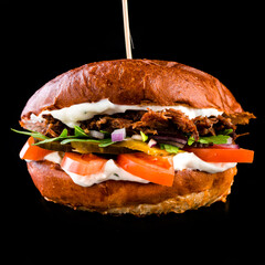 American burger with torn beef is isolated on a black background