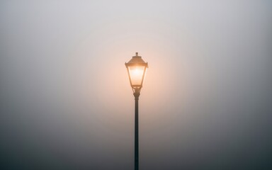 street lamp in the fog A single street lamp shines brightly through a thick fog.