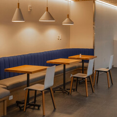 Three tables and seats in a corridor with lamps holding from ceiling.