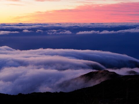 A breathtaking view of the vast sky moments after sunset, with rolling clouds gently covering the hills in a mesmerizing dance of light and colors - Pico do Arieiro, Madeira, Portugal.