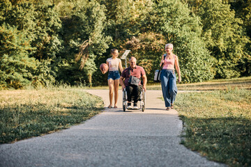 Family Walking In Park With Man With Disability