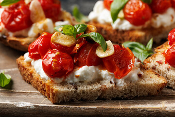 Cottage cheese and roasted tomatoes sourdough bread toast on a wooden board.