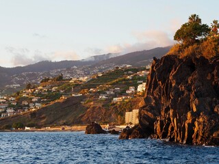 A scenic hillside village is seen under the warm afternoon sunlight, with terraced houses and lush...