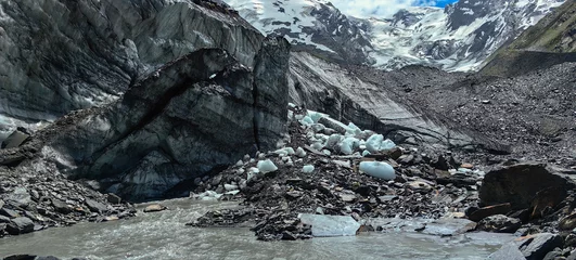 Fototapete Rund Melting of a mountain glacier and large blocks of snow on the Alibek glacier in Dombai, in the Karachay-Cherkess Republic, Russia. © Elena