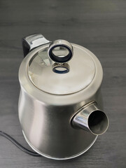 Closeup of a modern, brushed steel and chrome electric kettle, standing on its own.