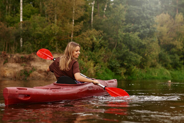 A Joyful Young Woman Kayaking on a Serene Lake, Completely Surrounded by Beautiful Nature