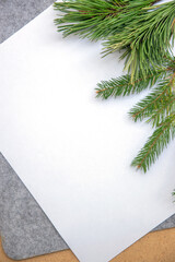 Blank white sheet of paper with fresh pine leaves on a textured background, perfect for holiday crafts or invitations in a cozy setting