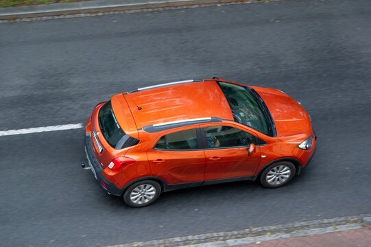 Orange Opel Mokka A crossover driving on street, motion blur effect