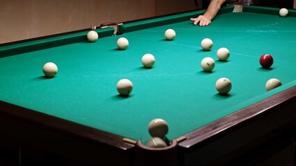 Playing Russian billiards on a green table. Billiard player hits the white ball. Good goal. Successful attempt. A great game. Hobby pastime. Corner pocket side view close-up. Professional shot