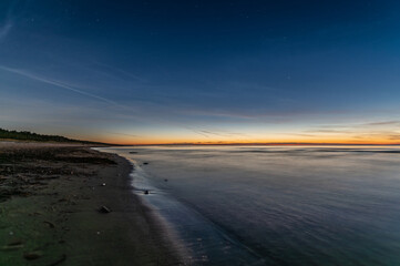 Baltic sea beach in Latvia at Autumn after sunset, stars and Comet C 2023 A3 Tsuchinshan–ATLAS far away in the sky.