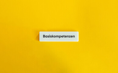 Basic Competence. German Text on Block Letter Tile on Yellow Background. Minimal Aesthetic.