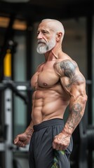Fototapeta premium An elderly man with a beard, and tattoos, proudly displays his strong physique while working out. Elderly man showcasing impressive physique during workout session in modern gym