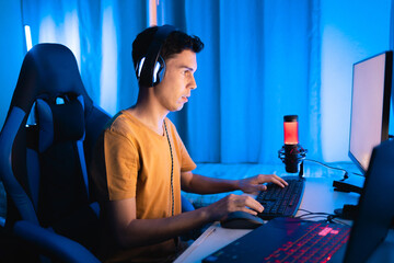 Focused gamer playing an intense online match at home. Surrounded by colorful tech gear, headphones, and neon lighting, perfect for streaming or esports tournaments