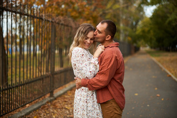 Fototapeta premium Beautiful and happy couple hugging and smiling while enjoying their time in Autumn Park