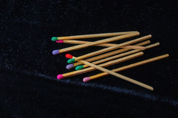 oversized wooden matches with colorful sulfur heads, arranged like a palette against a dark background, symbolizing creativity and the spark of inspiration