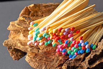 vibrant collection of oversized wooden matchsticks with colorful sulfur heads rests upon the texture of aged wood, symbolizing the interplay of fragility and resilience