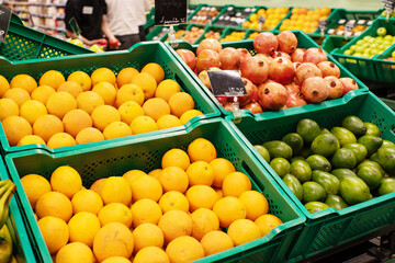 Various fresh fruits, oranges, kiwi, pomegranates in boxes on store shelves, vegetable market.
