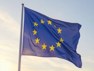 The European Union flag waves gracefully against a soft evening sky. The blue field with twelve golden stars represents unity among the EU nations.