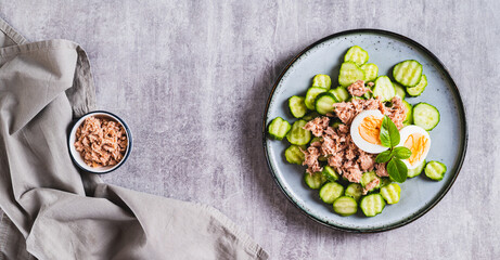 Keto salad with tuna, cucumber, egg and basil in a bowl on the table top view web banner