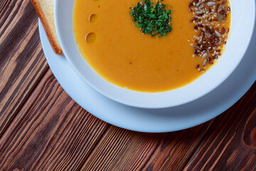 Vegetable soup with bread on wooden tray. White bowl on dark plank background. Top view. Copy space.